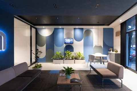 Pared del fondo pintada como bandas verticales cerradas con medios círculos en azules, grises y crema, que repiten el arco del monograma