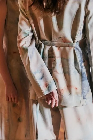 Prenda de la colección cápsula con NERATTA, estampada con una pintura de Belén Marcuzzi, en tonos naranja, gris claro.