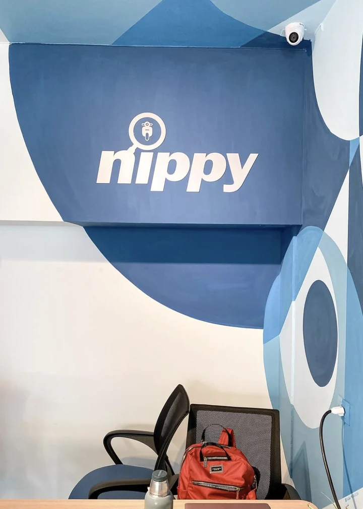 Vista cercana del logotipo de Nippy pintado dentro del campo azul más oscuro del mural, donde la geometría envuelve un buzón